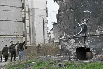  ?? — AFP ?? Message of peace: residents looking at the girl gymnast graffiti.