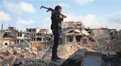  ?? MOHAMAD ABAZEED/AFP/GETTY IMAGES ?? A rebel fighter stands amid the rubble of destroyed buildings Tuesday in the rebel-held area of Daraa, Syria.