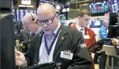  ?? Richard Drew/Associated Press ?? Trader Jeffrey Vazquez, center, works on the floor of the New York Stock Exchange Oct. 26.