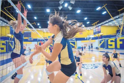  ?? EDDIE MOORE/JOURNAL ?? Salome Romp, center, a junior with the Demonettes, hits the ball across the net at practice on Wednesday.