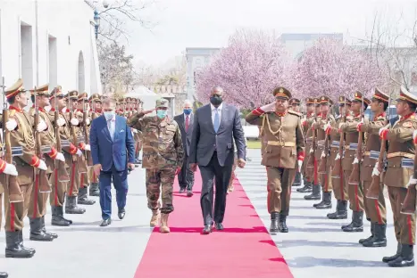  ?? PRESIDENTI­AL PALACE ?? Defense Secretary Lloyd Austin, center, walks with Afghan officials as they review an honor guard Sunday in Kabul, Afghanista­n. Austin arrived in Kabul amid swirling questions about how long U.S. troops will remain in the country.