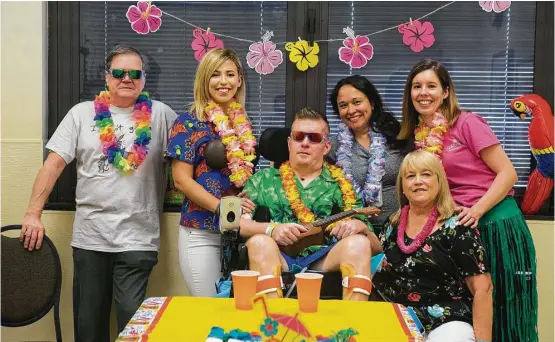  ?? Mark Mulligan / Houston Chronicle ?? James Tullier, from left, Danielle McNicoll, Nick Tullier, therapists Carissa Ngo and Kelly Betts, and Mary Tullier celebrate Nick’s 42nd birthday with a Hawaiian-themed party at TIRR Memorial Hermann.