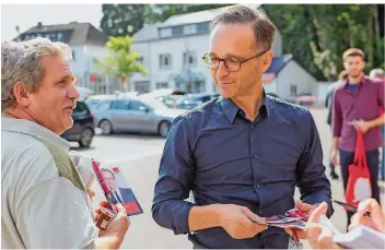  ?? FOTOS: RICH SERRA ?? Bierernst war gestern: Heiko Maas (SPD) sorgt in seinem Wahlkampf für gelöste Stimmung – hier plaudert er mit Menschen vor einem Lebensmitt­elmarkt in Beckingen.