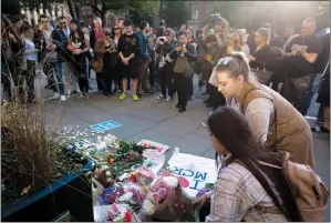  ?? AP PHOTO EMILIO MORENATTI ?? People lay flowers after a vigil in Albert Square, Manchester, England, Tuesday, the day after a suicide attack at an Ariana Grande concert that left 22 people dead.