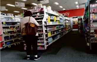  ?? JOE RAEDLE/GETTY IMAGES ?? A customer at a CVS Health store in Miami Tuesday. The Woonsocket, R.I.based company employed more than 300,000 people as of 2022.