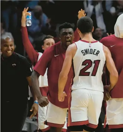  ?? MARTA LAVANDIER/AP ?? The Miami Heat cheer their teammates during the second half of a preseason game against the Charlotte Hornets, Tuesday, in Miami. The Heat defeated the Hornets 113-109.