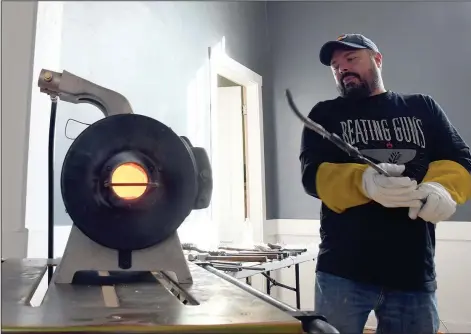  ?? (AP/Thomas Peipert) ?? Michael Emmert, a volunteer blacksmith for the nonprofit group RAWtools, puts a rifle barrel into a forge Jan. 16 at a church in Denver.