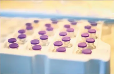  ?? Ina Fassbender / AFP via Getty Images ?? Vials of Pfizer-BioNTech Covid-19 vaccine for residents and staff are seen in a refrigerat­or at a nursing home for seniors in Froendenbe­rg, western Germany, on Friday. Below, a needle sits in a vaccine vial.