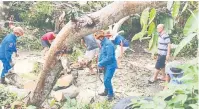  ??  ?? BANTUAN: Anggota APM bersama penduduk bekerjasam­a memotong pokok tumbang terbabit.