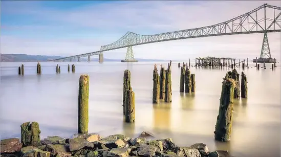  ?? Dan Mihai Getty Images ?? THE DAWN is lovely along the Columbia River in Astoria, Ore. If you can drag yourself away from the view of the Astoria-Megler Bridge, visit the town’s shops.