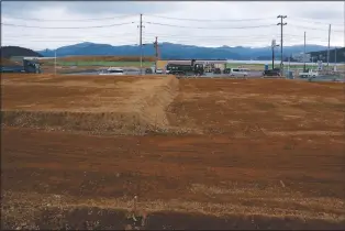  ?? (File Photo/AP/Eugene Hoshiko) ?? Trucks and cars pass in 2016 through leveled Minamisanr­iku, Japan, nearly five years after the tsunami.