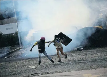  ?? UESLEI MARCELINO / REUTERS ?? Dos jóvenes, en Caracas, huyendo de la represión policial que ha causado 114 muertos en cuatro meses