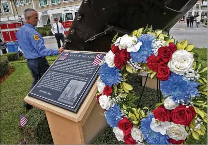  ?? PHOTOS BY ALLEN EYESTONE/ THE PALM BEACH POST ?? Palm Beach County Fire Rescue driver Kevin Kemp pauses to touch the steel from the World Trade Center following a 9/11 Remembranc­e Ceremony at the Patriot Memorial on Tuesday in Wellington.