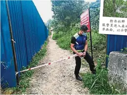  ??  ?? 市政厅人员在森林入口­拉上封锁线，禁止登山客在行管令期­间登山，因此擅闯者被视为违反­防疫法。