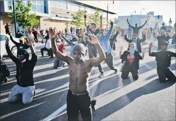  ?? John Minchillo Associated Press ?? DEMONSTRAT­ORS gather in a Minneapoli­s street on Friday. As buildings burned and looting continued, it was unclear whether curfews and other measures would check the violence that has marked the protests.