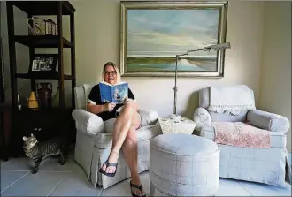  ?? AP PHOTO/WILFREDO LEE ?? Kelly Vaiman poses for a photo in her living room where she sometimes likes to sit and read, Friday, Feb. 19, 2021, in Boynton Beach, Fla. Vaiman is an avid cozy mystery reader.