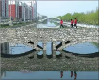  ?? WANG ZHUANGFEI / CHINA DAILY ?? Residents walk across a bridge near a residentia­l area in Anxin county in Xiongan New Area on Wednesday. All housing sales in the new area have been banned.