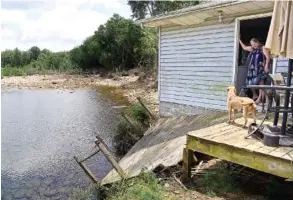  ?? STAFF PHOTO BY ROBIN RUDD ?? Sandra Hayes talks to one of her dogs over the deck that has collapsed down the bank of North Chickamaug­a Creek at her Pine Street home in Soddy-Daisy.