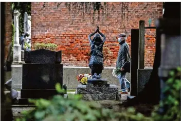  ?? FOTO: CLAUDIO FURLAN/DPA ?? Beerdigung­en finden in Zeiten der Corona-Pandemie nur noch im kleinen Rahmen statt. Viele Menschen müssen einsam trauern – so wie dieser Mann, der an Allerheili­gen alleine über den Friedhof läuft.