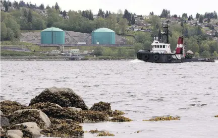  ?? JONATHAN HAYWARD/THE CANADIAN PRESS FILES ?? A tug boat chugs past the Kinder Morgan Marine Terminal in B.C. Many British Columbians are increasing­ly uncomforta­ble with a decade of pipeline wars that are harming the province’s attractive­ness as a place to do business, writes Claudia Cattaneo.