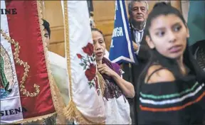  ??  ?? Evelyn Arellano, front, 15, of Friendship, Yadira Jimenez, 54, of Beechview, and Enrique Bazau, back, of Squirrel Hill, peek down the aisle during the Our Lady of Guadalupe Mass.