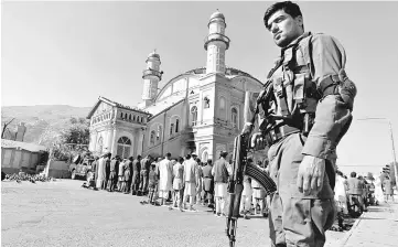  ??  ?? A policeman stands guard as men perform Aidiladha prayers in Kabul, Afghanista­n. — Reuters photo