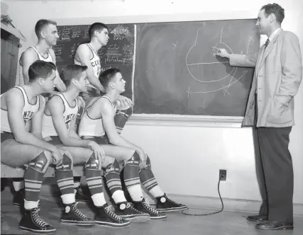  ?? THE COMMERCIAL APPEAL FILES ?? Feb. 16, 1952: Central High School’s starting unit consisting of (seated from left) Herbie Kosten, Jerry Cobb, Walter Streuli, (standing from left) Loring Henley and John Dickerson looks on as coach Lloyd Mcdougal diagrams a play.