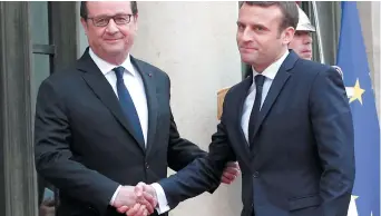  ??  ?? Emmanuel Macron et son prédécesse­ur François Hollande se sont donné une poignée de main devant des centaines de journalist­es. - Associated Press