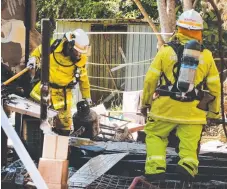  ??  ?? Firies remove one of the gas bottles after a blaze gutted the Hope Island home on Saturday night.