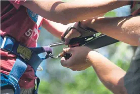  ??  ?? Safety equipment is attached to a zipliner at AVA Colorado Ziplining. Colorado began regulating the zipline industry six years ago.