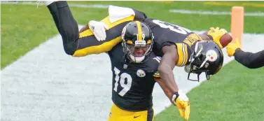  ?? AP ?? JuJu Smith-Schuster spins James Washington on his shoulders after the latter’s TD reception against the Browns.