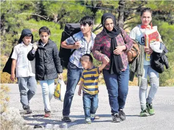  ??  ?? Refugees fleeing Syria and surroundin­g war torn areas controlled by ISIS arrive on the island of Lesbos from Turkey. People on the road on the island.