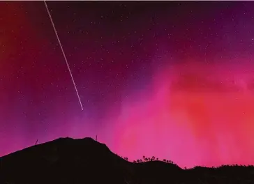  ?? Carlos Avila Gonzalez/The Chronicle ?? The blinking lights of a plane streak through the aurora borealis, also known as the northern lights, visible late Friday over Lake Berryessa in Napa County because of a geomagneti­c storm.