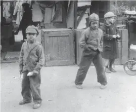  ??  ?? Poor children play in the streets in “World City in Its Teens,” a documentar­y made by a German writer-photograph­er in Depression-socked Chicago.