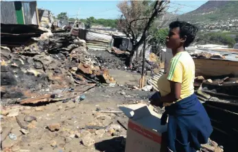  ?? PICTURE: HENRIETTE GELDENHUYS ?? A week after the big blaze, Silindokuh­le Khonkco rests with a donation box while inspecting the fire damage close to where her shack was burnt down.