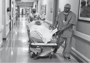  ?? Kin Man Hui / Staff photograph­er ?? Anesthesia technician Ty Stoddard, right, and registered nurse Richard Esquivel escort patient Yolanda Ledesma to the same-day surgery operating room at Mission Trail Baptist Hospital.