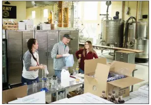  ?? (AP/Matt Rourke) ?? Caitlin Bagenstose (from left), Logan Snyder and his wife, Carly Snyder, bottle hand sanitizer Monday at the Eight Oaks Farm Distillery in New Tripoli, Pa. The distillery’s owner, Chad Butters, is temporaril­y converting his operation into a production line for the suddenly hard-to-find, alcohol-based disinfecta­nt.