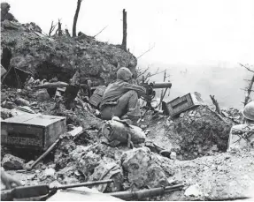  ?? ASSOCIATED PRESS ?? This undated photograph shows a U.S. Marine operating a water-cooled .30 caliber machine gun in protection of his comrades advancing during the invasion of Okinawa island in 1945.