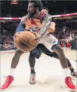  ?? TROY WAYRYNEN / USA TODAY SPORTS ?? Washington Wizards guard John Wall keeps the ball away from Portland Trail Blazers’ CJ McCollum during the second half of Monday’s NBA game at Moda Center in Portland, Oregon. Wall had 16 points and nine assists as the Wizards won 125-124 in overtime.