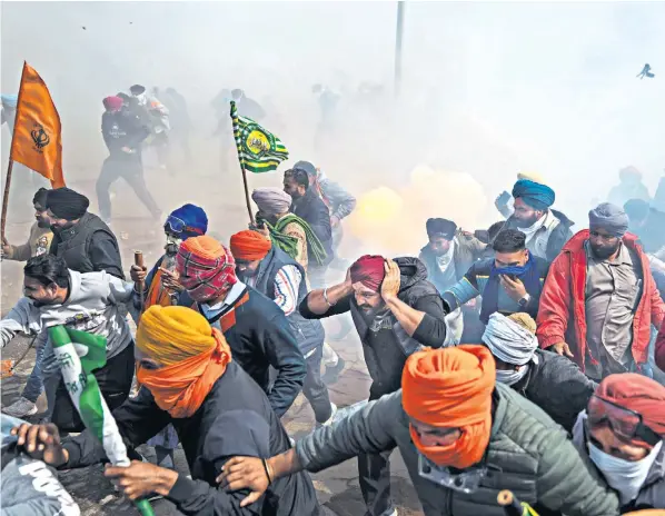  ?? ?? Protesting farmers demanding higher prices for their crops run from exploding tear gas shells fired by the police. Trouble flared outside Shambhu village on the Punjab state border, 125 miles north of New Delhi
