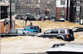  ?? Libby Solomon ?? The Associated Press Water rushes Sunday through Main Street in Ellicott City, Md. Flash flooding and water rescues were being reported in Maryland as heavy rain soaks much of the state.