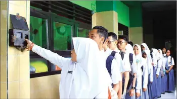  ?? SHELA TAMARA/JAWA POS ?? BUDAYA RAPI: Siswa-siswi SMA Antartika Sidoarjo berjajar rapi untuk absensi sidik jari sebelum masuk kelas.