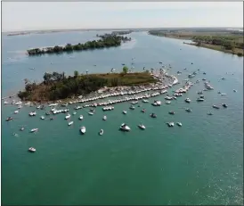  ?? SCREENSHOT COURTESY OF WXYZ-TV ?? The number of boats gathered around Gull Island around noon Friday appeared to be significan­tly less than recent years.