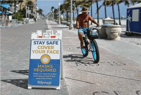  ?? Mike Stocker / Tribune News Service ?? Infectious disease experts are urging continued use of safety measures, including face masks and social distancing, as fall and winter get underway. Signs along the boardwalk remind beach visitors Wednesday in Hollywood, Fla.