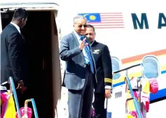  ??  ?? Dr Mahathir waves before boarding the special flight back to Malaysia. — Bernama photo