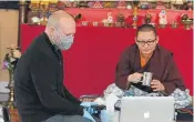  ??  ?? Temple member Joe Stone, left, helps Lhoppšn Rinpoche get connected before the meditation.
