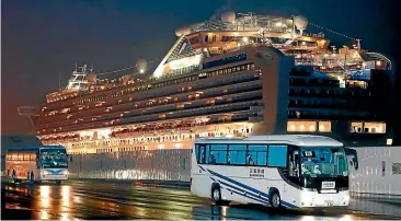  ?? AP ?? Buses carrying US passengers who were aboard the quarantine­d cruise ship the Diamond Princess, seen in background, leave Yokohama port, near Tokyo, early yesterday. The cruise ship was carrying 3700 passengers and crew members under quarantine.