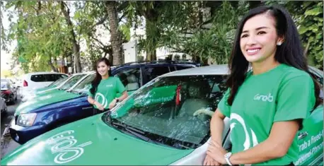  ?? AFP ?? Models stand beside Grab cars in Phnom Penh during the ride-hailing firm’s launch in December.