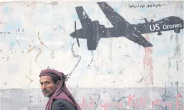  ?? REUTERS ?? A man walks past a graffiti denouncing strikes by US drones in Yemen, painted on a wall in Sana’a, Yemen, on Feb 6.