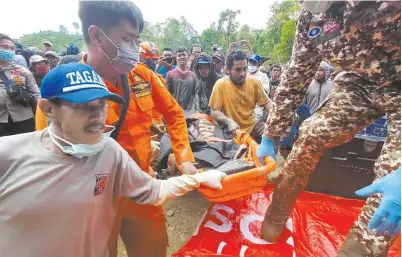  ??  ?? Rescue teams carry the body of a miner yesterday after an illegal gold mine collapsed in the village of Buranga on the Indonesian island of Sulawesi. — AFP